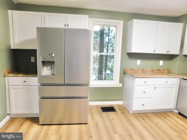 a kitchen with a refrigerator and white cabinets