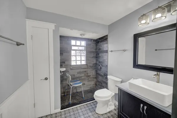 a bathroom with a sink a toilet a mirror and shower