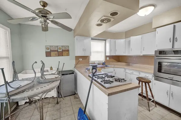 a kitchen with a stove a sink cabinets and wooden floor