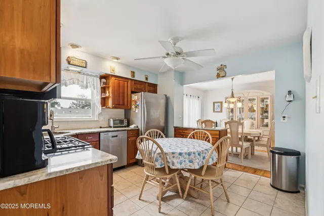 a kitchen with stainless steel appliances granite countertop a stove refrigerator and chairs