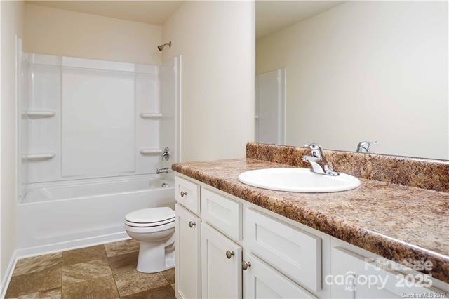 9740 Weikert Road Charlotte, NC 28215 - Photo 12 of 16 a bathroom with a granite countertop sink toilet a mirror and bathtub