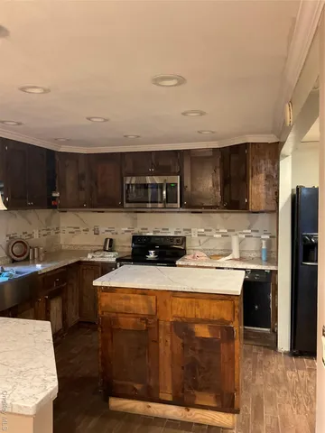 a kitchen with stainless steel appliances granite countertop a stove a sink dishwasher and a refrigerator with wooden floor