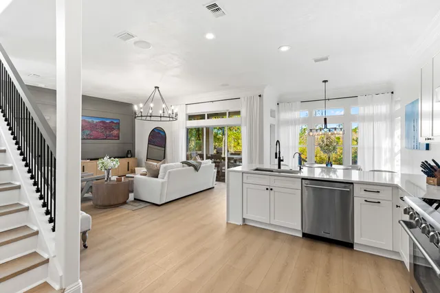 a living room with stainless steel appliances furniture a chandelier and wooden floor