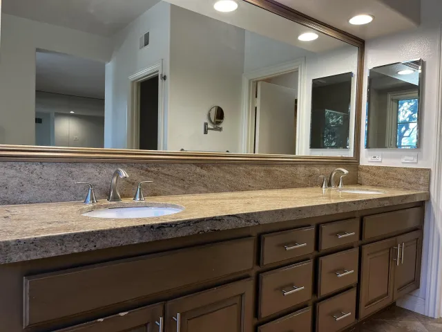 a bathroom with a granite countertop sink double and mirror
