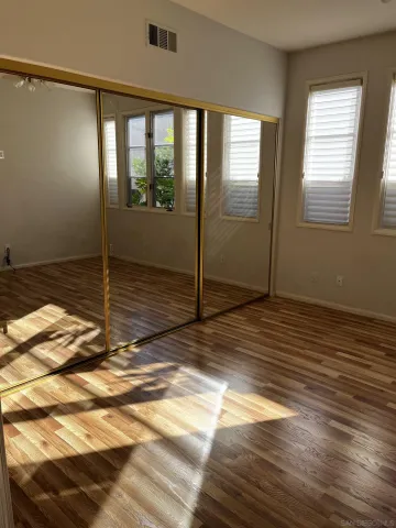 a view of empty room with wooden floor and fan