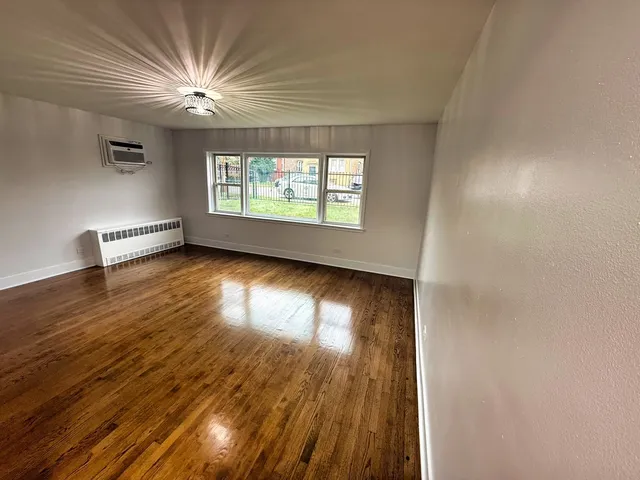 an empty room with wooden floor chandelier and windows