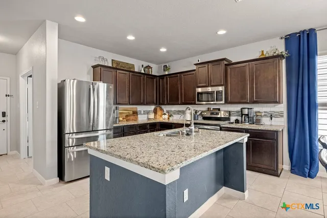a kitchen with kitchen island granite countertop stainless steel appliances and wooden cabinets