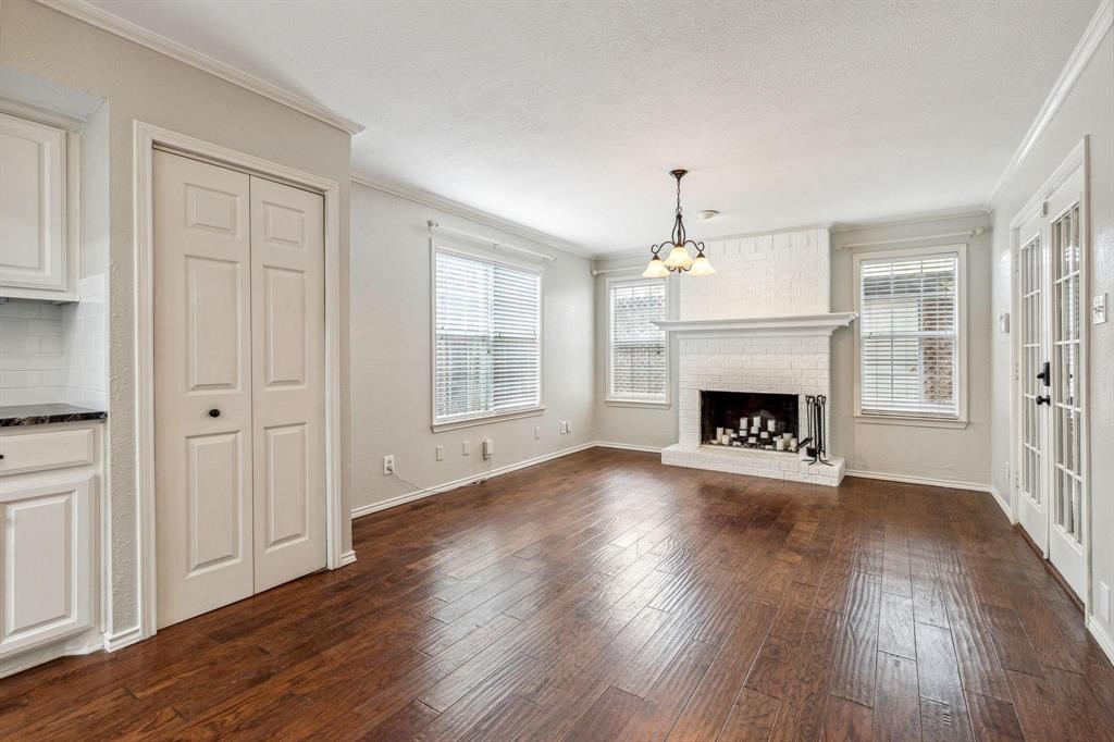 Unfurnished living room with crown molding, plenty of natural light, dark wood-style floors, and an inviting chandelier