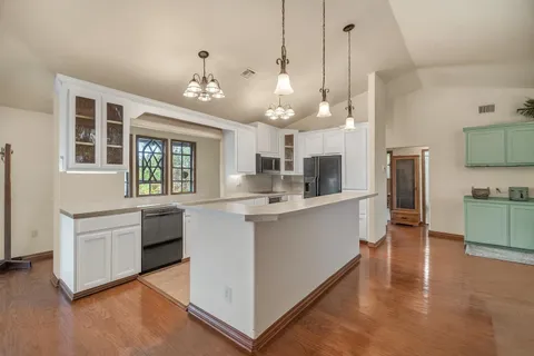 a large kitchen with kitchen island white cabinets and stainless steel appliances