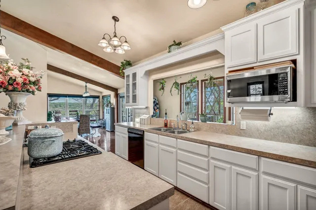 a kitchen with stainless steel appliances granite countertop a sink dishwasher a stove and a dining table with wooden floor