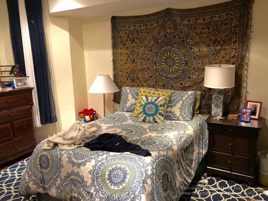 a bedroom with a bed and a lamp on dresser