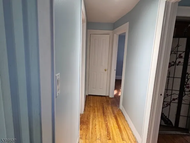 a view of a hallway with wooden floor and a bathroom