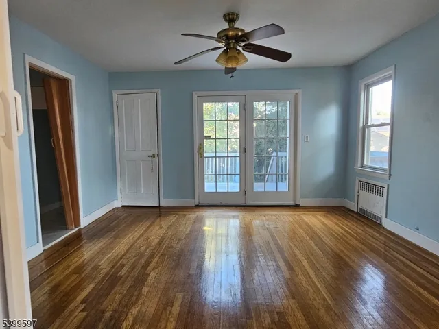 a view of an empty room with a window and wooden floor