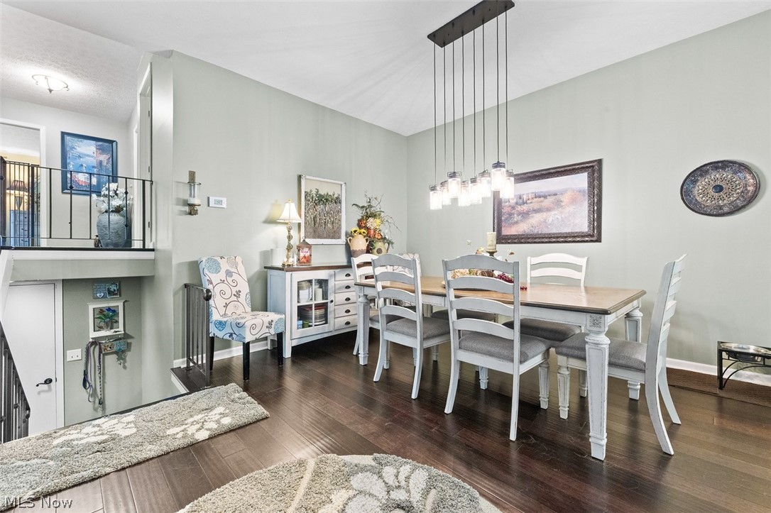 171 Granger Road, Unit 107 Medina, OH 44256 - Photo 14 of 41 Open-concept dining area featuring dark bamboo wood flooring, a contemporary linear pendant light fixture, a light-toned dining table with seating, and a built-in sideboard cabinet with glass-front doors