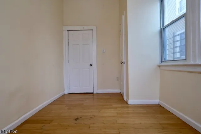 a view of an empty room with wooden floor and closet