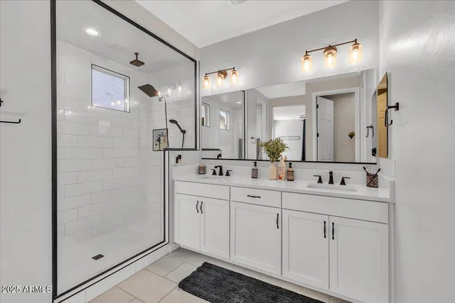 a spacious bathroom with a double vanity sink a mirror and shower