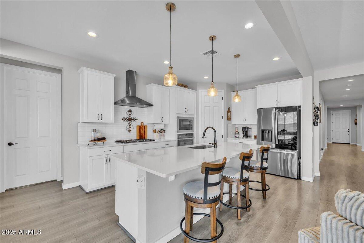 17593 West Red Fox Road Surprise, AZ 85387 - Photo 8 of 55 a large kitchen with stainless steel appliances kitchen island granite countertop a stove a sink a refrigerator and a dining table with wooden floor