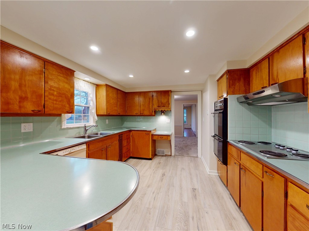 145 Overlook Road Painesville, OH 44077 - Photo 24 of 36 Kitchen with decorative backsplash, wood finish cabinetry, light countertops, light wood-style flooring, and stainless steel electric cooktop