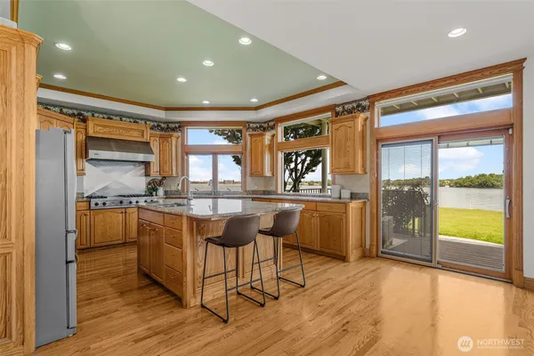 a kitchen with stainless steel appliances kitchen island granite countertop a table chairs in it and wooden floors