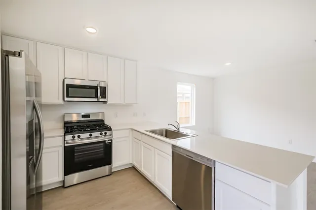a kitchen with granite countertop a sink stove and microwave