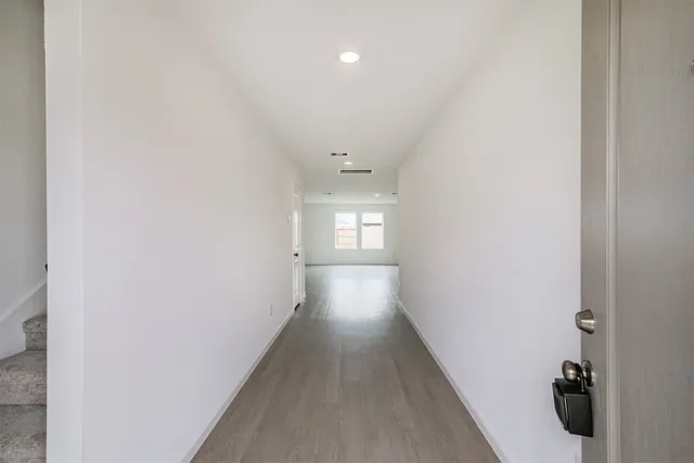 a view of a hallway with wooden floor and a bathroom