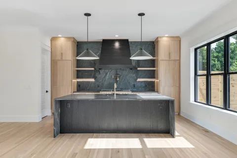 a kitchen with stainless steel appliances granite countertop a sink a stove and a wooden floor