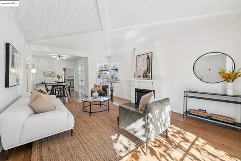 a living room with furniture a fireplace kitchen view and a wooden floor