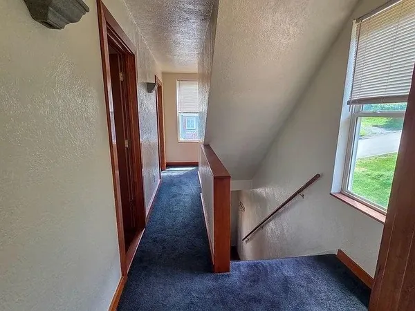a view of a hallway with wooden floor and staircase