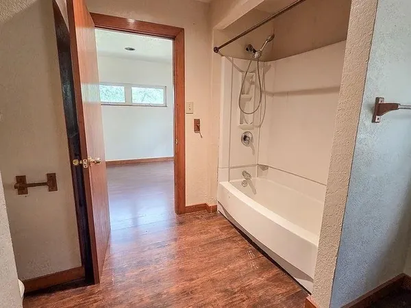 an empty room with wooden floor cabinet and windows