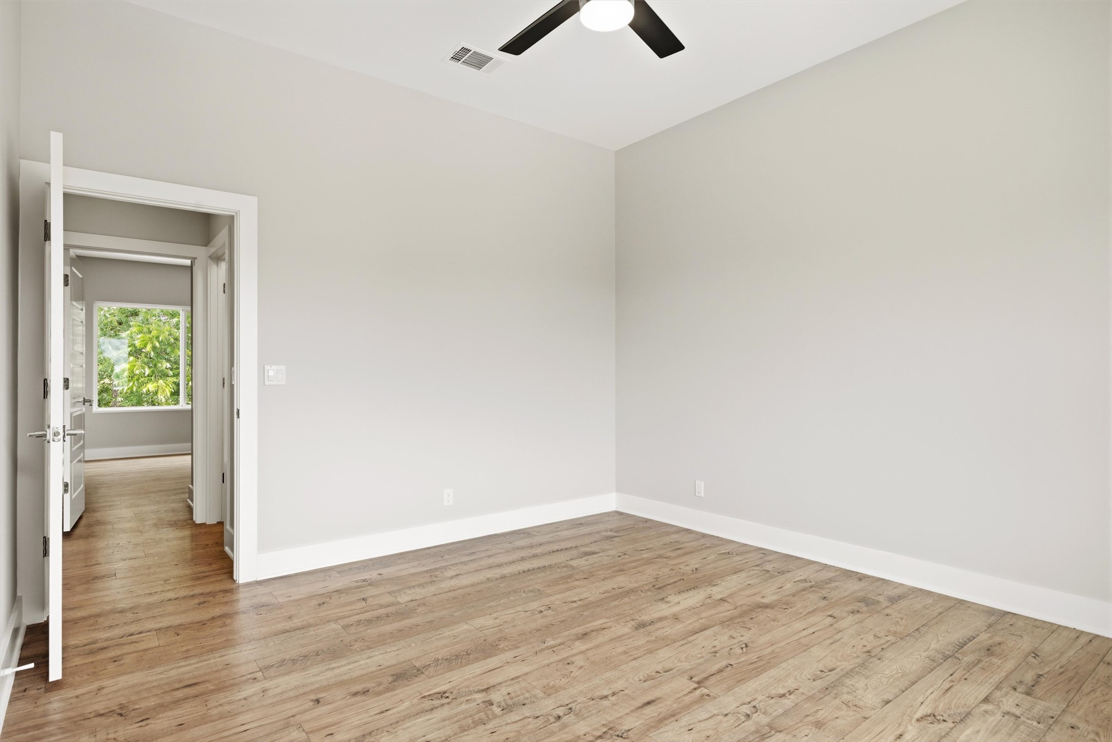 1210 Stobaugh Street, Unit B Austin, TX 78757 - Photo 6 of 40 Natural light filters into this spacious room, featuring elegant wood flooring and a modern ceiling fan.