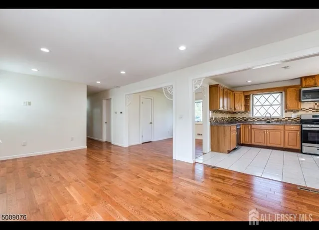 a kitchen with stainless steel appliances granite countertop a stove top oven a refrigerator a sink dishwasher and wooden cabinets with wooden floor