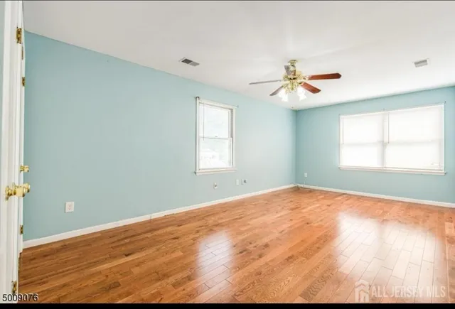 an empty room with a window and ceiling fan
