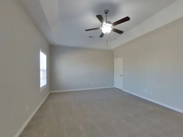 an empty room with windows and fan