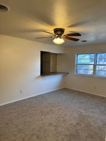 an empty room with windows and chandelier fan