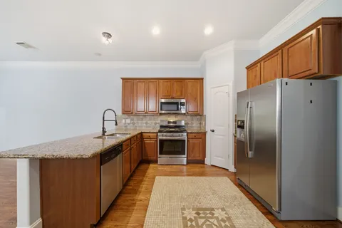 a large kitchen with stainless steel appliances granite countertop a stove a refrigerator and a sink