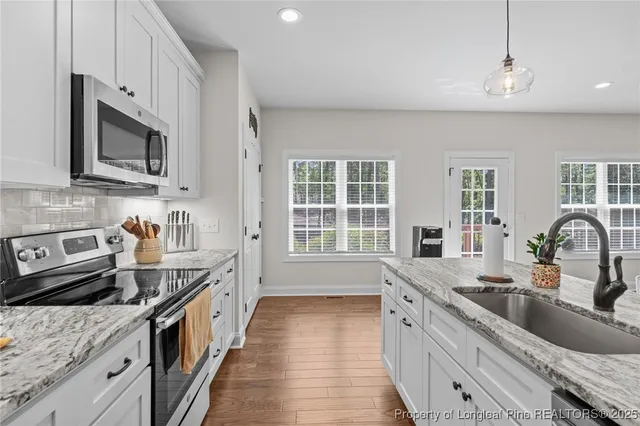 a kitchen with stainless steel appliances granite countertop a sink stove and microwave