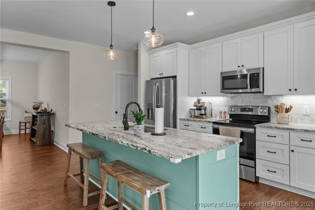 a kitchen with kitchen island granite countertop stainless steel appliances a stove a sink a microwave a refrigerator and cabinets