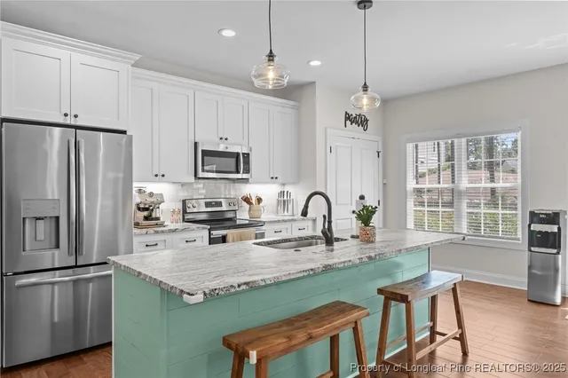 a kitchen with granite countertop a stove a refrigerator a sink dishwasher a dining table and chairs with wooden floor