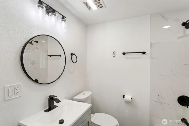a bathroom with a sink mirror and toilet