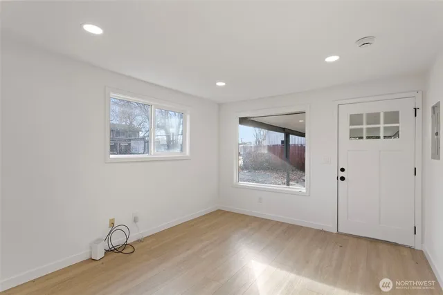 a view of an empty room with wooden floor and a window