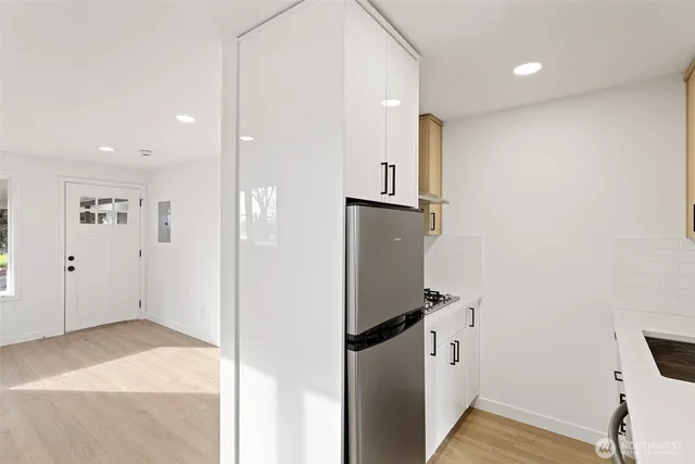 a view of a kitchen with refrigerator and wooden floor