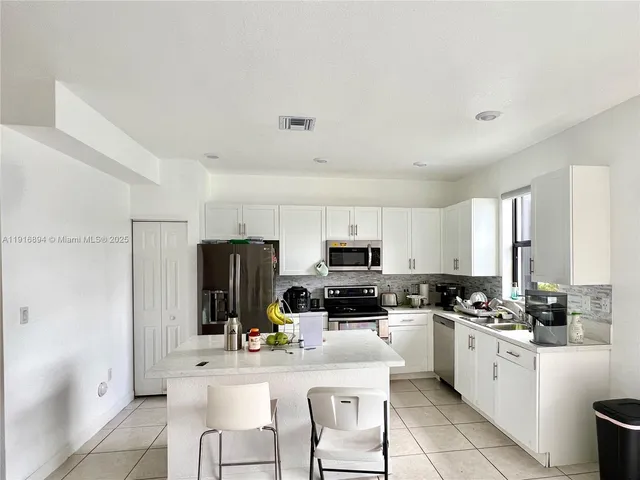 a kitchen with kitchen island a white cabinets and refrigerator