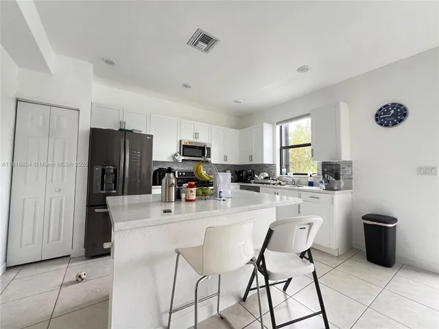 a kitchen with stainless steel appliances a refrigerator a stove a sink dishwasher and white cabinets with wooden floor