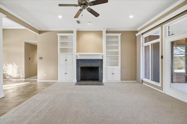 an empty room with chandelier fan and windows