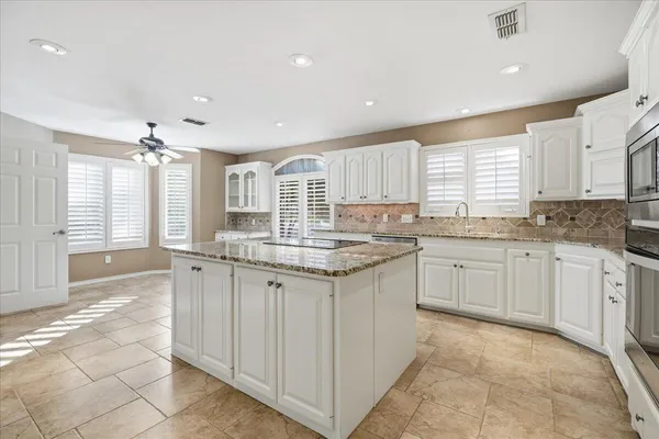 a view of a kitchen with white cabinets and outdoor space