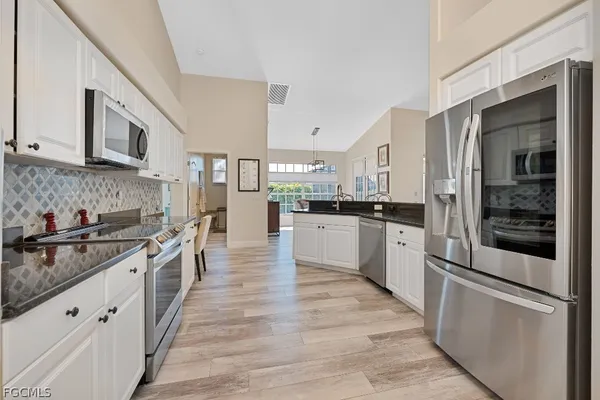 a large kitchen with stainless steel appliances granite countertop a stove and a refrigerator
