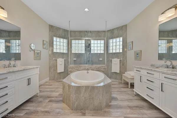 a spacious bathroom with a double vanity sink a bathtub a mirror and a bathtub