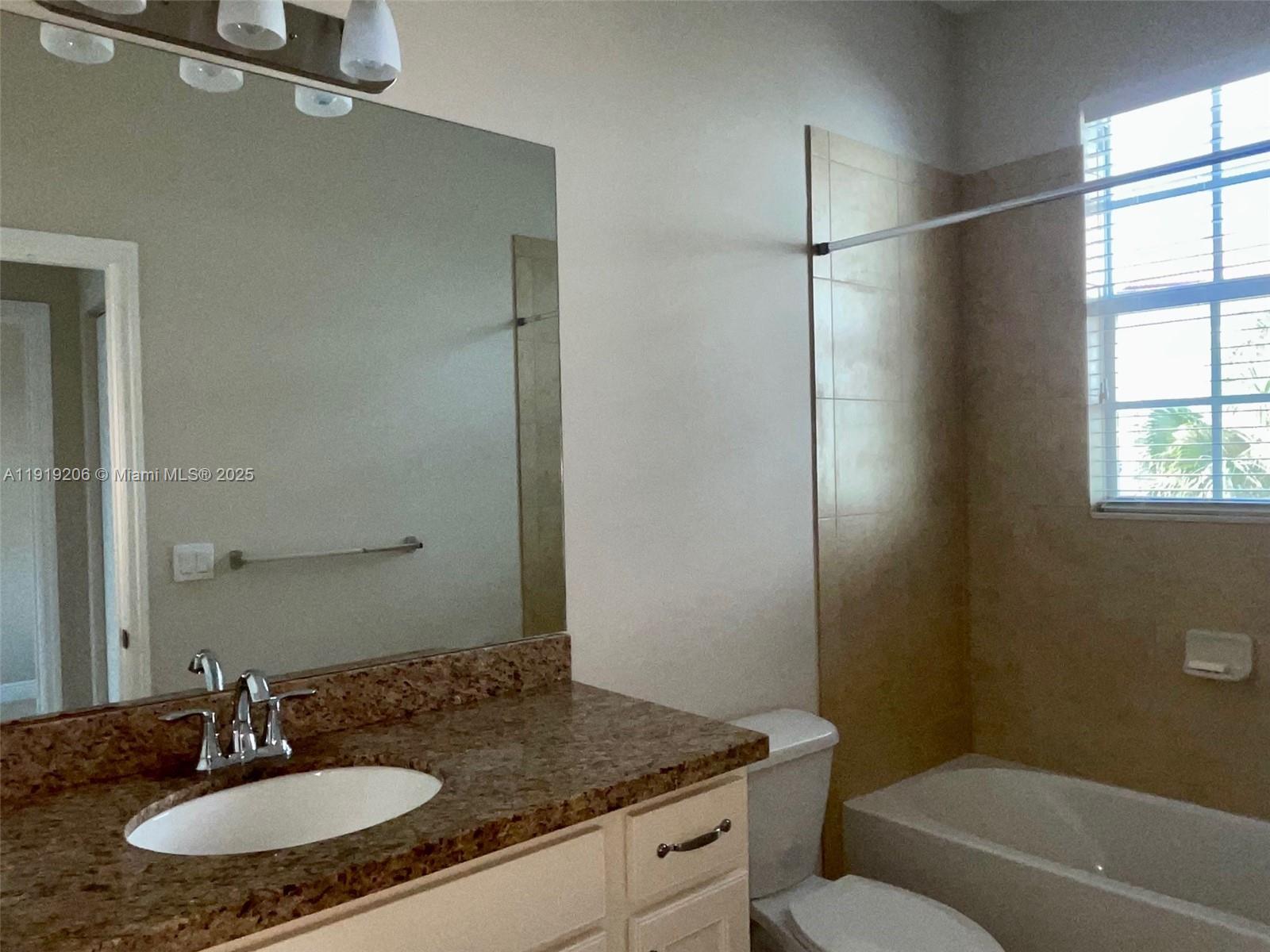 2929 Southwest 119th Way, Unit 2929 Miramar, FL 33025 - Photo 14 of 26 a bathroom with a granite countertop sink a toilet a mirror and shower