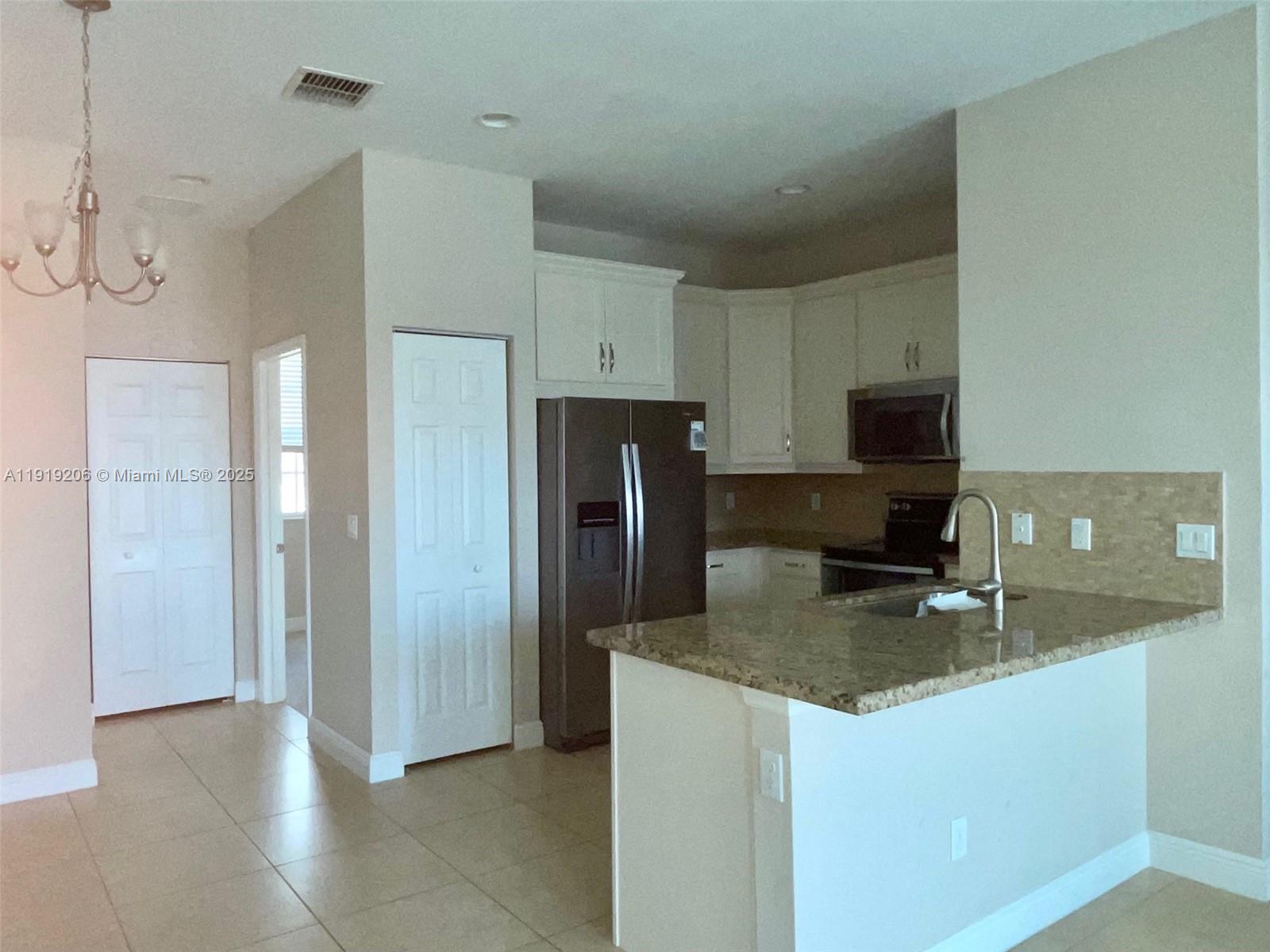 2929 Southwest 119th Way, Unit 2929 Miramar, FL 33025 - Photo 8 of 26 a kitchen with stainless steel appliances granite countertop a refrigerator a stove a sink a microwave and cabinets