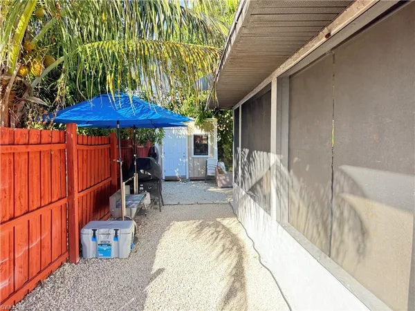 a view of a patio with table and chairs under an umbrella with a small yard